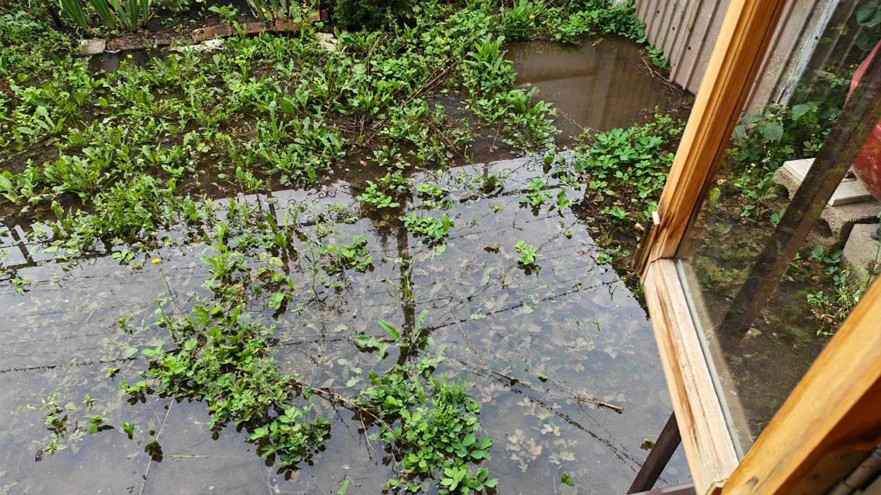 После прорыва трубы холодного водоснабжения дворы затоплены; опасность — наклоняющаяся опора ЛЭП. Жители улицы Металлистов пытаются откачать воду.